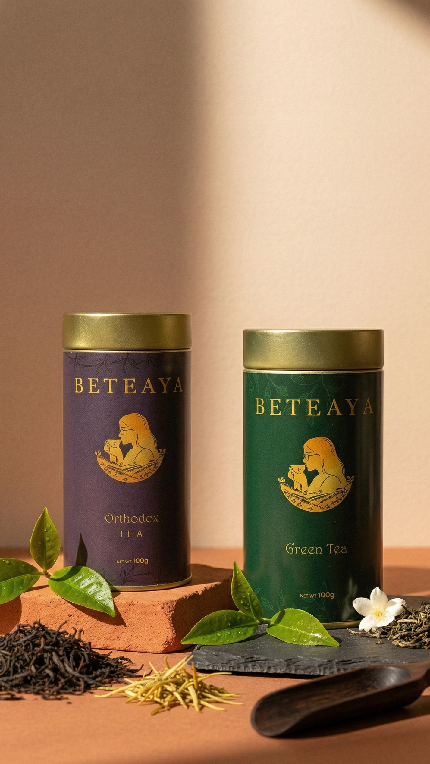 Green tea and Black Tea canisters labeled 'Beteaya' with tea leaves and a spoon on a wooden surface.